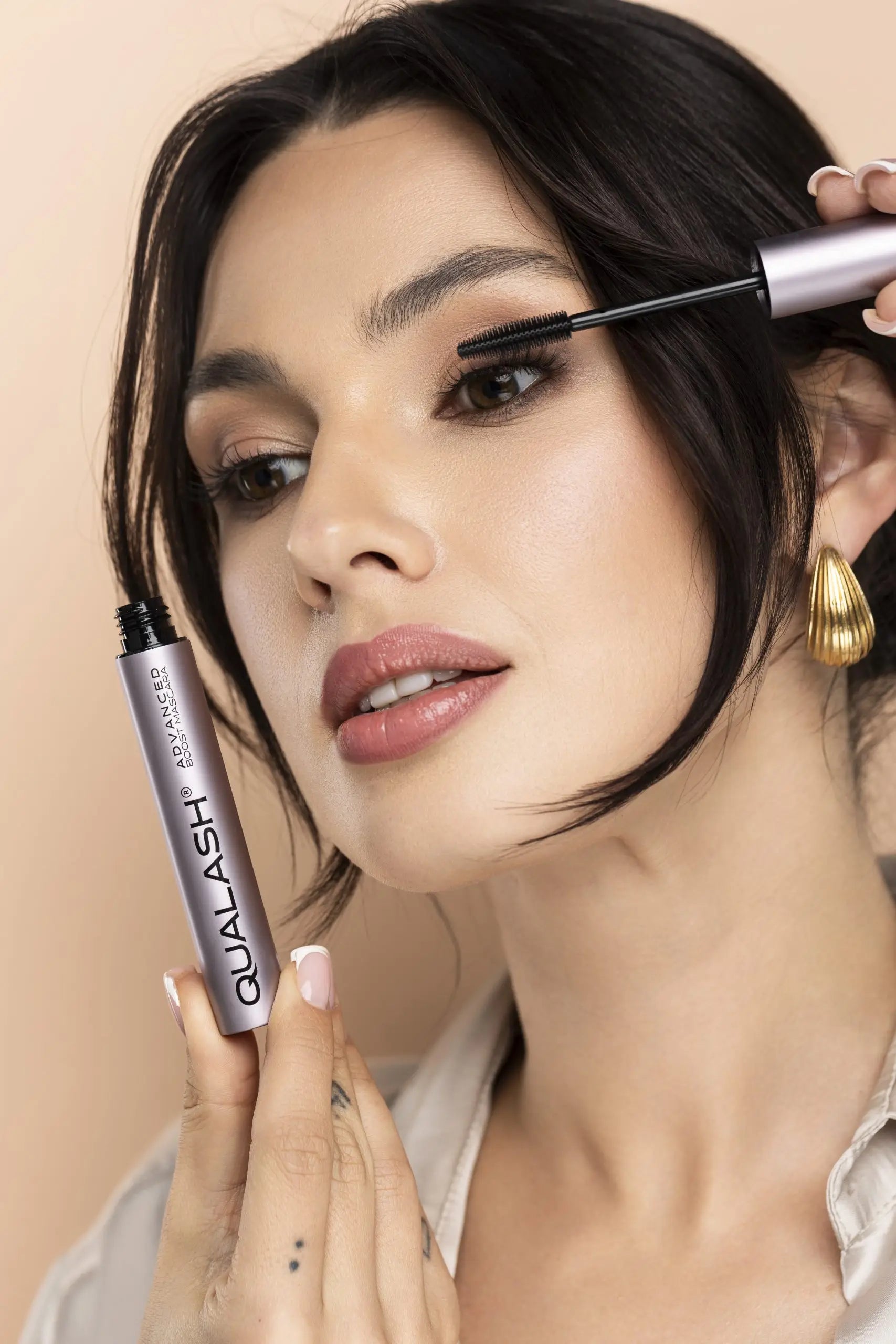 Femeie zâmbitoare ținând QUALASH Advanced Mascara Volume Max după aplicare – Pasul 2