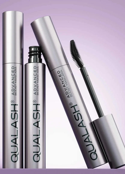 Multiple QUALASH Curl &amp; Lift mascaras arranged creatively on soft purple background with focus on brush and tube